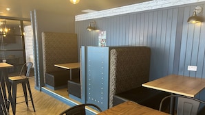 A restaurant interior with booth seating, wooden tables, and pendant lighting. - Electric Press  (Sheffield)