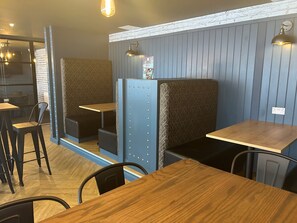 Ein Restaurantinnenraum mit Sitzecken, Holztischen und Pendelleuchten.