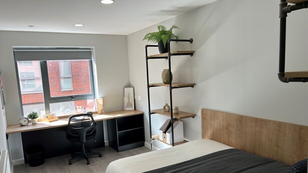 A modern bedroom with a bed, desk, chair, and shelving unit. - Electric Press  (Sheffield)