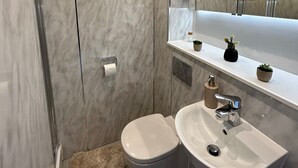 A modern bathroom with a glass shower enclosure, a toilet, and a sink with a mirror above. - Electric Press  (Sheffield)