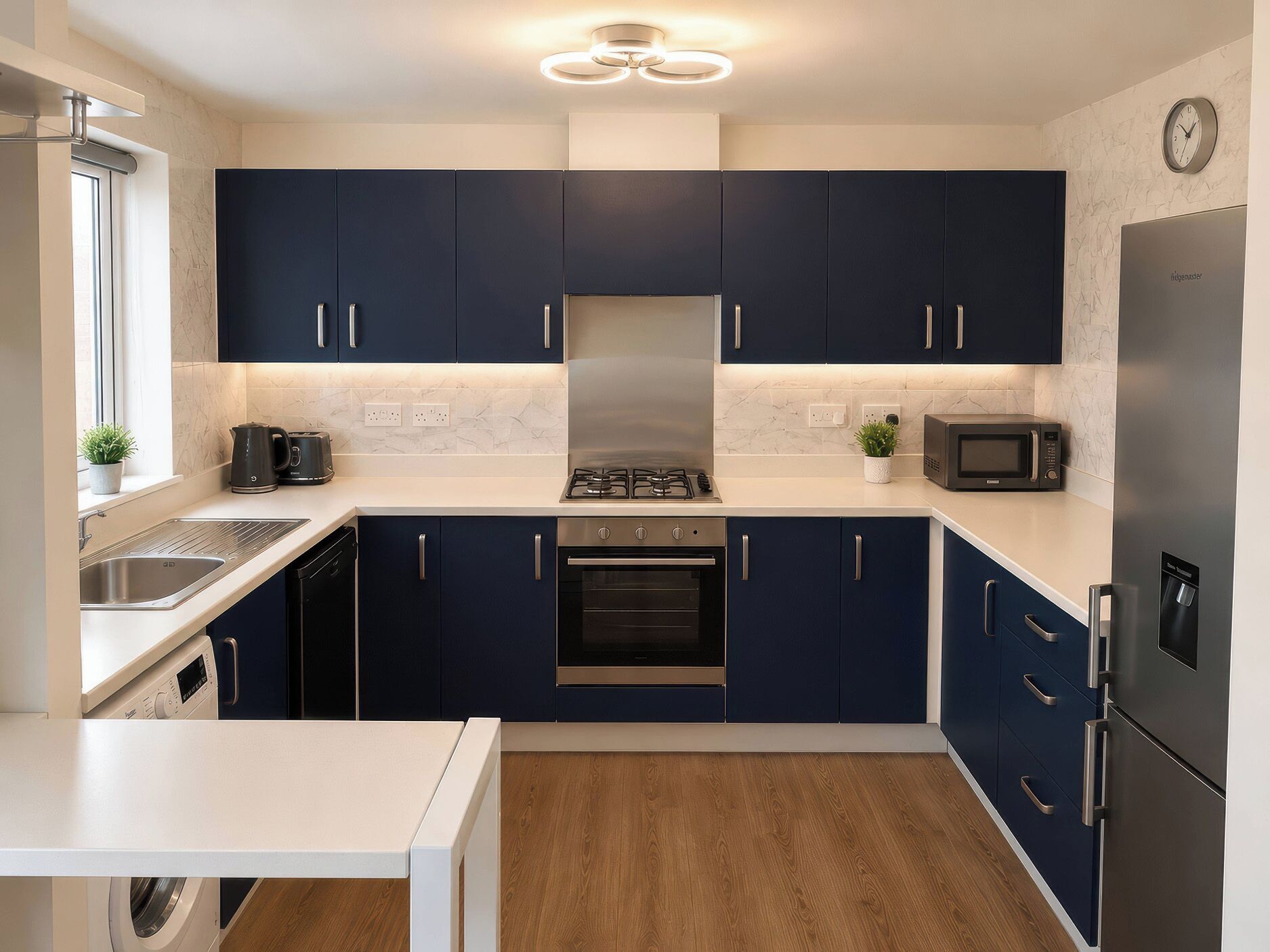 A modern kitchen with dark blue cabinets, a stainless steel range hood, a built-in oven, a microwave, and a dishwasher.