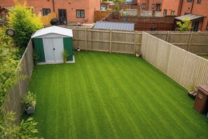 A well-maintained backyard with a green lawn, a shed, and a wooden fence.