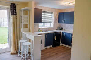 A compact kitchen with a sink, a coffee maker, and a window with blinds.