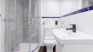 Ein modernes Badezimmer mit einer gläsernen Duschkabine, einer weißen Toilette und einem Waschbecken mit Spiegel darüber.