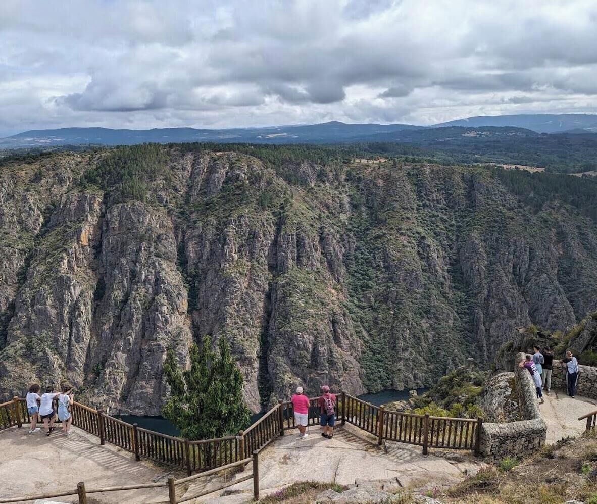 Paisaje montañoso con una plataforma de observación y barandas de madera.