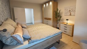 Une chambre à coucher avec un lit, des tables de chevet, une armoire et un miroir.