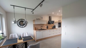 Une cuisine moderne dotée d’un plan de travail en bois, d’appareils électroménagers intégrés et d’un coin repas avec une table et des chaises.