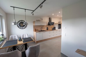 Eine moderne Küche mit Holzarbeitsplatte, integrierten Geräten und einem Essbereich mit Tisch und Stühlen.