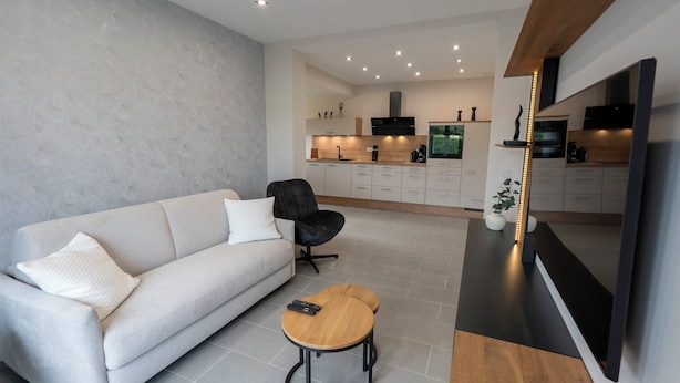 Un salon moderne avec un canapé, une table basse ronde et un téléviseur.