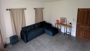 Una sala de estar con un sofá seccional, una mesita de madera con un cuadro y una puerta.