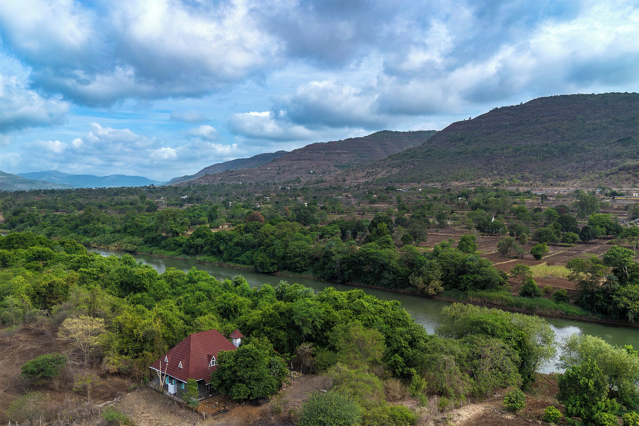 A river flowing through a valley with a house near the water.