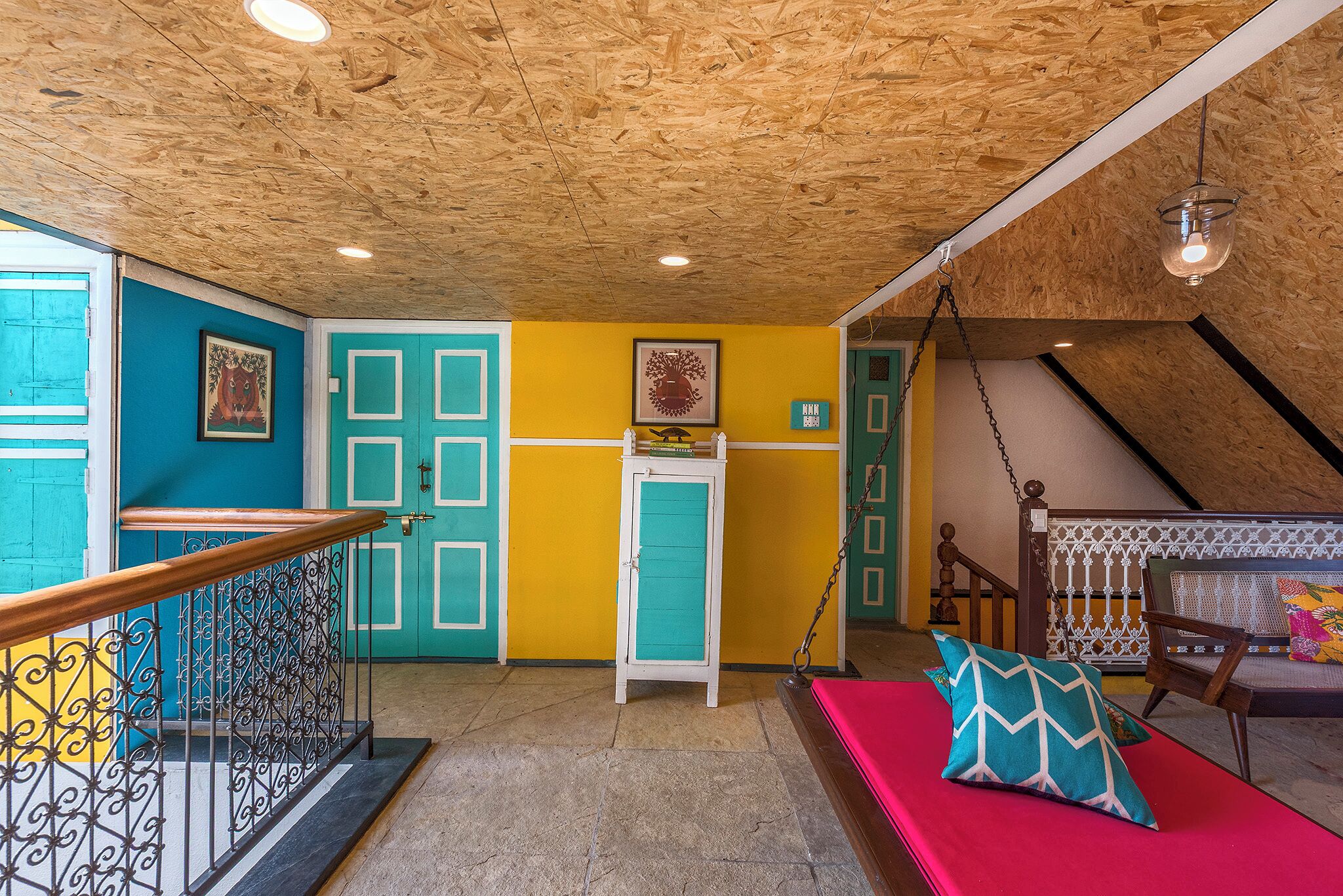 A room with a wooden ceiling, a red sofa, a turquoise cabinet, and a staircase.
