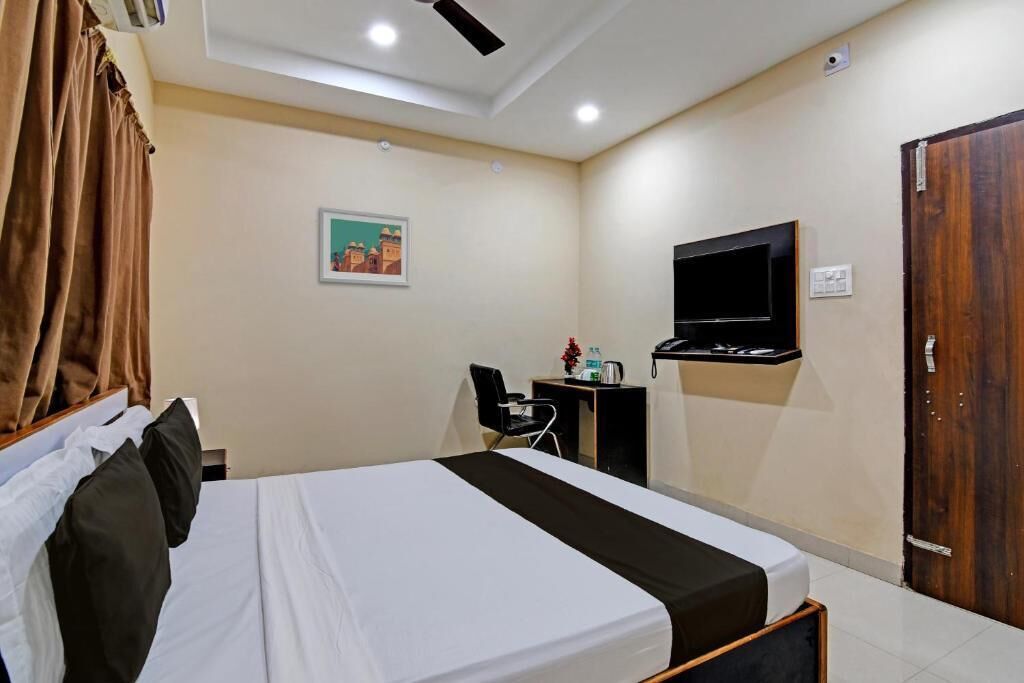 Une chambre d’hôtel comprenant un lit, un bureau avec une chaise, un téléviseur fixé au mur et une porte.
