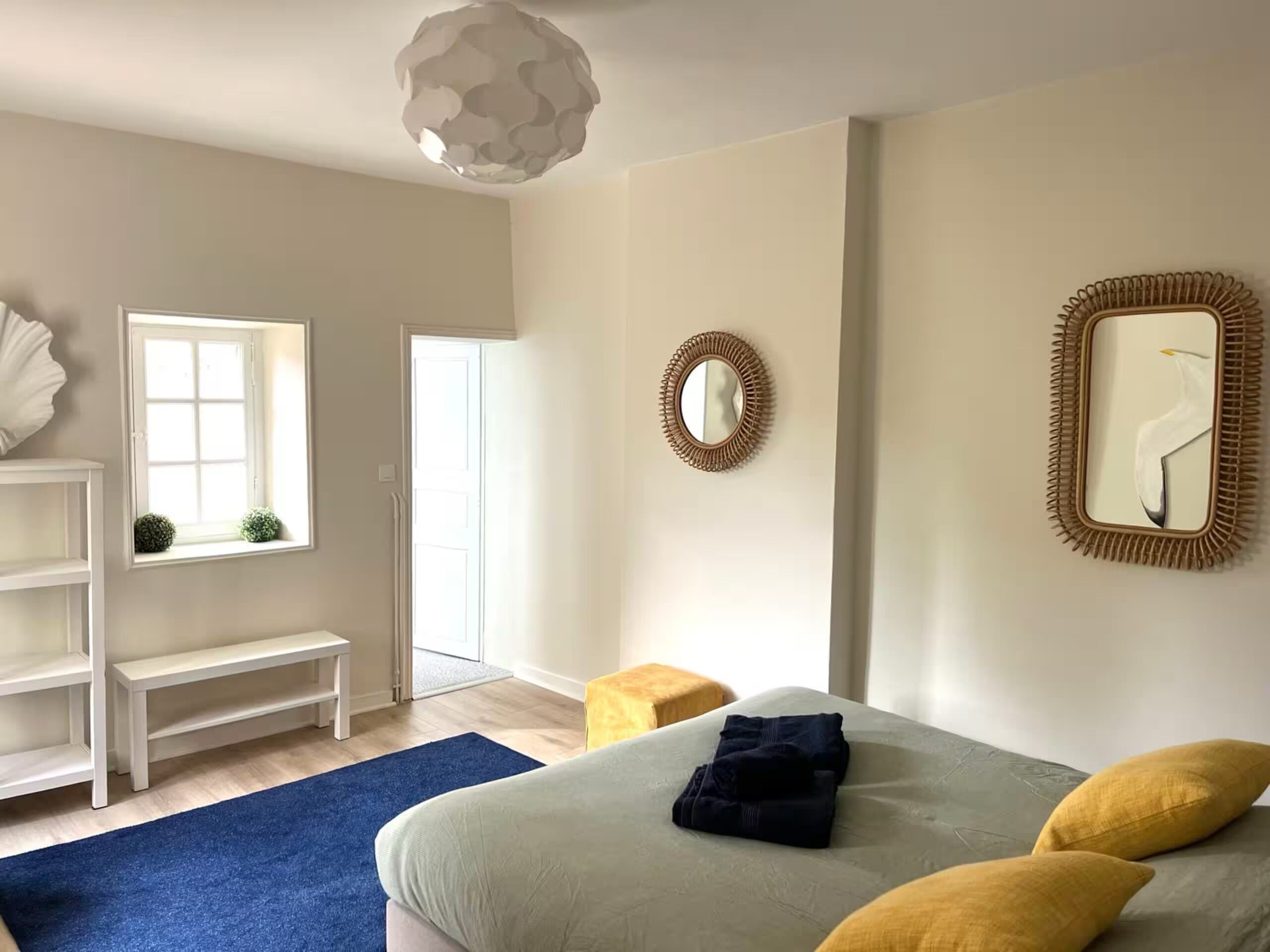 A bedroom with a bed, a bench, a mirror, and a door.