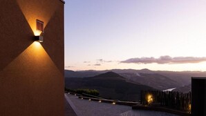 Un bâtiment doté d’un toit en pente et offrant une vue sur une vallée, avec des montagnes à l’horizon.