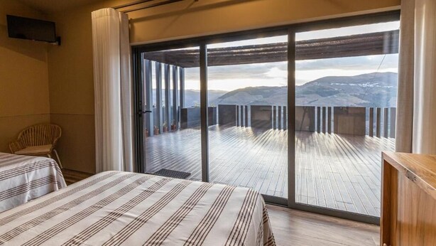 Une chambre d’hôtel avec deux lits, un balcon offrant une vue sur les montagnes et un plancher en bois.