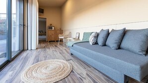 Un salon moderne avec un canapé gris, un tapis tissé et une vue dégagée grâce à de grandes fenêtres.