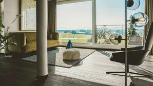 A modern living room with a large window, a sofa, a chair, and a lamp. - Water tower with Alpine panorama in Chiemgau (Trostberg)