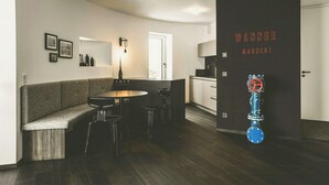 A modern kitchen with a built-in stove, a dining area with a bench and chairs, and a door with a water valve. - Water tower with Alpine panorama in Chiemgau (Trostberg)