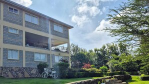 A multi-story building with a stone facade, a grassy lawn, and a stone staircase leading to a circular patio area.