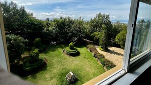 A view through a window of a well-maintained garden with manicured lawns and topiary.