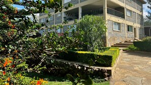 A multi-story building with balconies, a stone pathway, and well-maintained greenery.