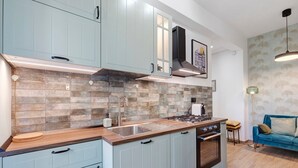 Une cuisine moderne avec des meubles de couleur bleu clair, un pare-feu en carreaux et une cuisinière à gaz intégrée.