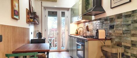 Een moderne keuken met een eethoek, een fornuis, oven en een hangplant.