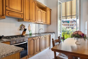 Una cocina con armarios de madera, encimera de granito, estufa y comedor con mesa y sillas.