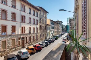 Una calle bordeada de coches aparcados y edificios con ventanas amuralladas.