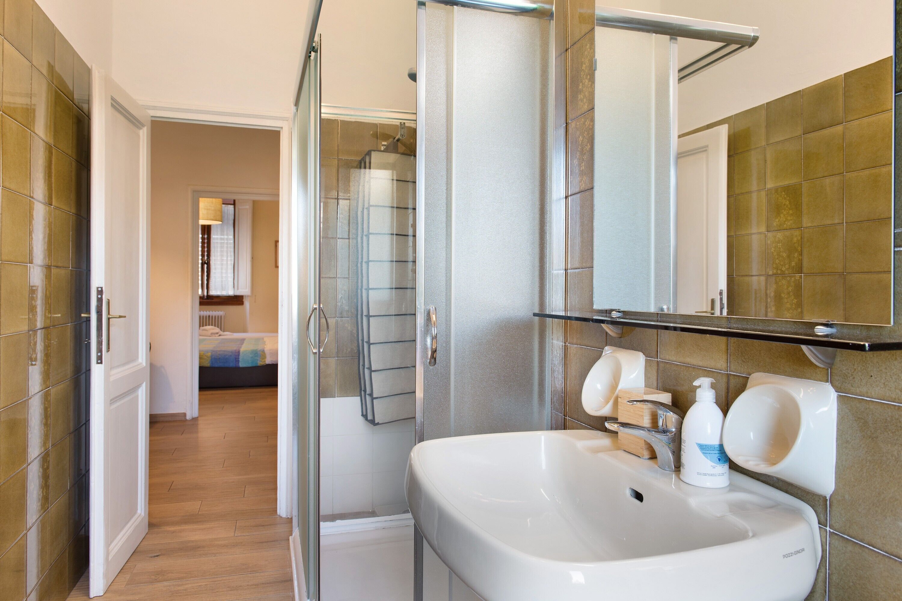 A bathroom with a white sink, a glass shower enclosure, and a mirror above the sink.