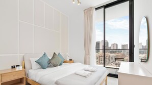 Ein modernes Hotelzimmer mit einem großen Bett, einem Nachttisch, einem Badezimmer mit Spiegel und Blick auf die Stadt.