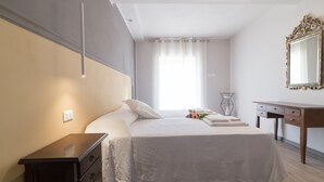 Ein Schlafzimmer mit einem Bett, einem Nachttisch, einer Kommode und einem Spiegel an der Wand.