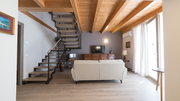 Eine Treppe führt zu einem Erkerraum mit einem weißen Sofa und einem Flachbildfernseher.