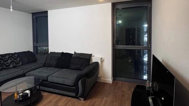 Una sala de estar moderna con un sofá modular, una mesa de centro de vidrio y un ventanal grande.