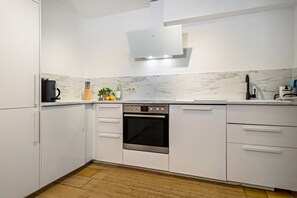 Eine moderne Küche mit weißen Schränken, einem eingebauten Ofen und einer Kaffeemaschine.