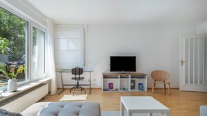 Una sala de estar moderna con sofá, mesa de centro, televisor y estantería.