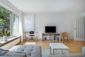 Ein modernes Wohnzimmer mit einer Couch, einem Couchtisch, einem Fernseher und einem Bücherregal.