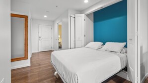 Una camera da letto con un letto, pavimento in legno, pareti bianche e una parete decorata in blu.