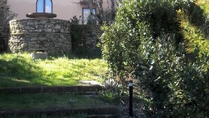 A two-story building with a stone facade, a blue roof, and a small garden area with steps leading up to the entrance. - Casina di Gabry (Toscana)