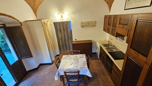 A compact kitchen with a dining area, a washing machine, and a view through a window. - Casina di Gabry (Toscana)