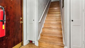 Un escalier avec des marches en bois menant à un palier, de part et d’autre duquel se trouvent des portes blanches et une porte en bois.