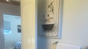 Un baño con una puerta blanca, un perchero para toallas y un lavamanos empotrado.