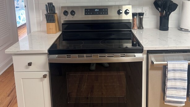 Una cocina con gabinetes blancos, microondas, horno y lavavajillas.