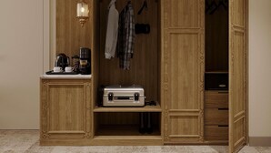 Un armario de madera con estante incorporado, barra para colgar y una mesita con cafetera y tazas.