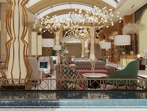 A hotel lobby with a pool, seating areas, and a decorative tree structure. - Mercure Khiva Hotel (Khiva)