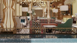 Un vestíbulo de hotel con piscina, zonas de estar y una estructura arbórea decorativa.