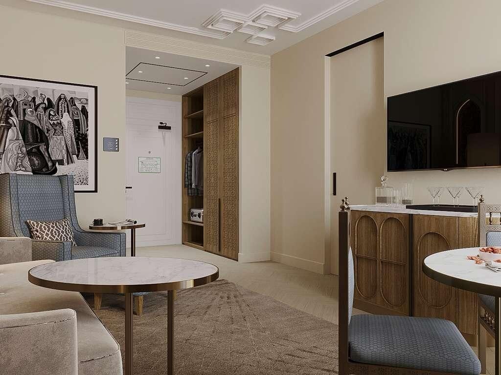 Una sala moderna con una mesa redonda, un área de descanso con un sillón tapizado en azul y un televisor de pantalla plana grande montado en la pared.