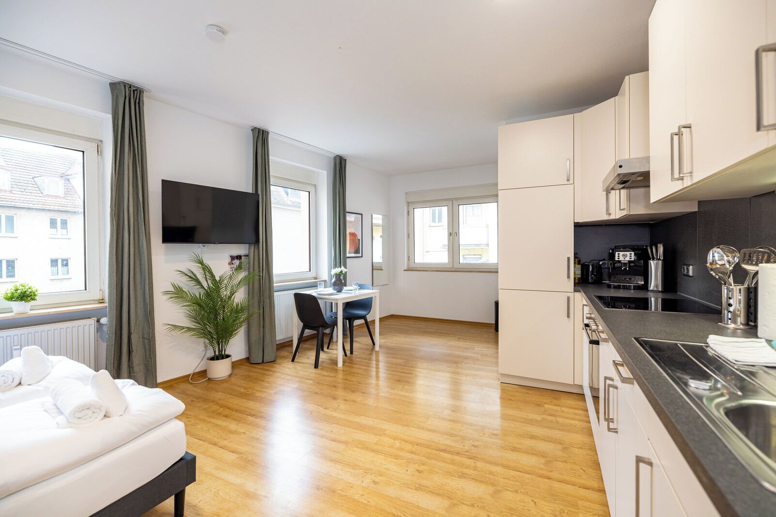 A modern apartment with a kitchen, dining area, and a bed.