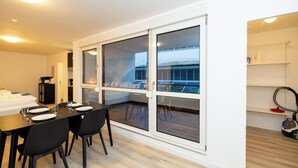 Habitación de hotel moderna con comedor, puertas correderas de vidrio y vista a un edificio.